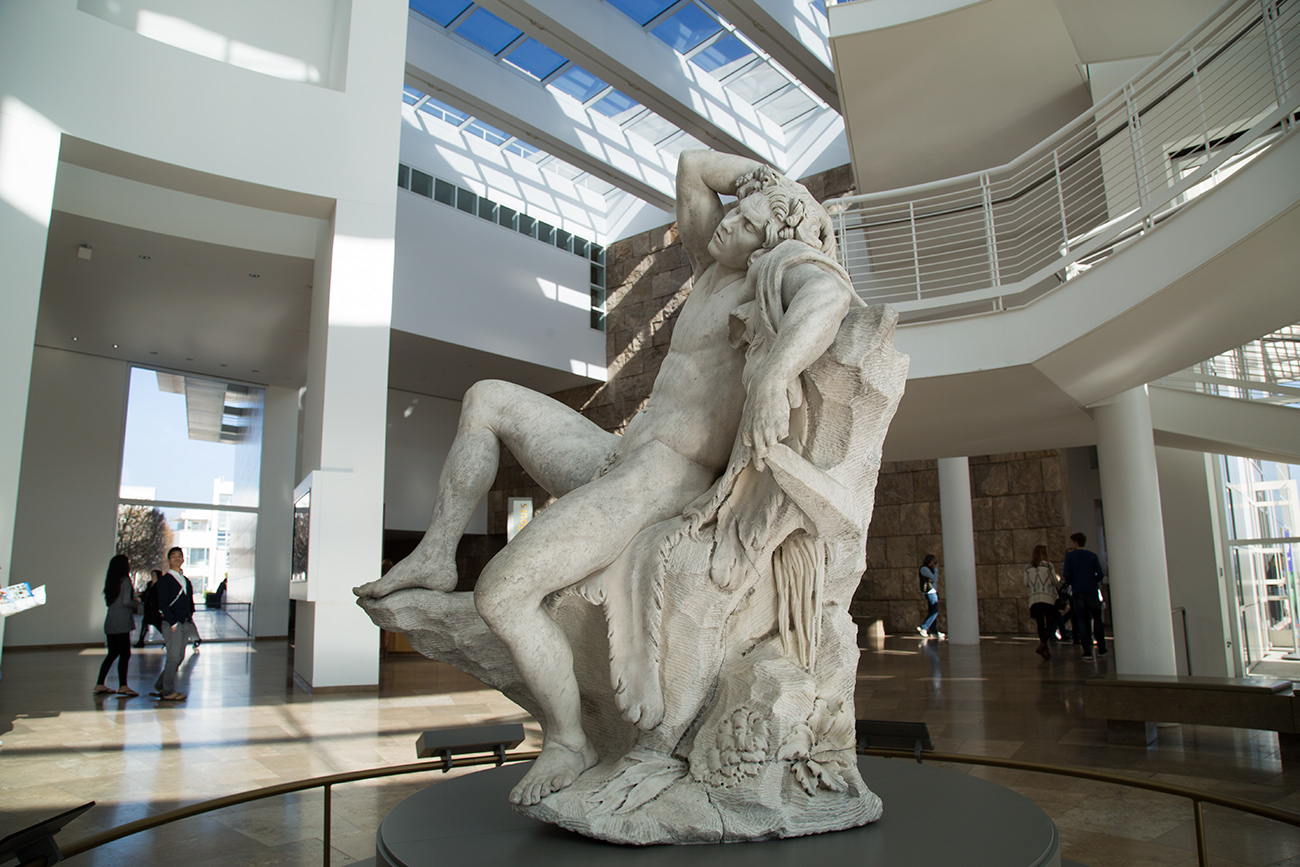 Over-life-size marble sculpture of a naked, reclining faun in the Getty Center's light-filled entry rotunda